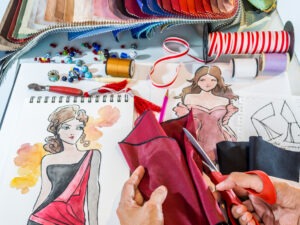 Fashion designer's hands working with material and hand-drawn illustration