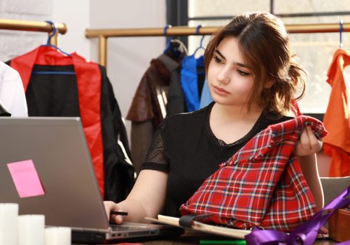 Young girl holding fabric and looking at her PC. High quality photo